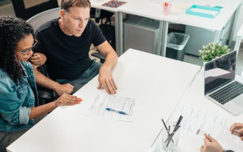 A couple discusses legal documents with a professional in a modern office setting.