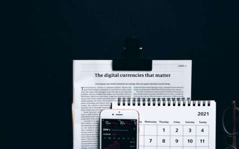 Digital currencies article with smartphone stock market app and calendar on black surface.